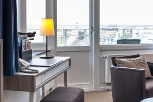 a room with a desk with a lamp and a chair at Hotel Neptun in Warnemünde