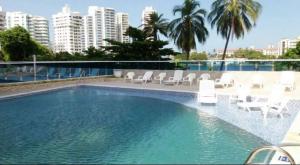 uma piscina com cadeiras, palmeiras e edifícios em Edificio Nuevo Conquistador em Cartagena de Indias