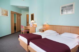 a hotel room with two beds and a desk at City Hotel Pilvax in Budapest