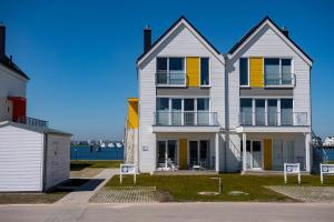 a large white house with yellow shutters on it at Hus Twustern in Olpenitz