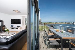a balcony with a table and chairs and a view of the water at Küsten Lodge in Olpenitz