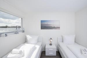 2 Betten in einem weißen Zimmer mit Fenster in der Unterkunft Schwimmendes Haus Bente in Olpenitz