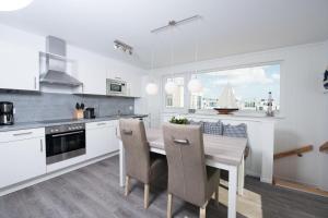 a white kitchen with a wooden table and chairs at Schwimmendes Haus Bente in Olpenitz