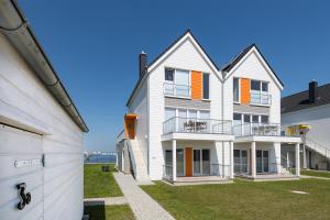 a large white house with orange shutters and a yard at Hafenlodge in Olpenitz