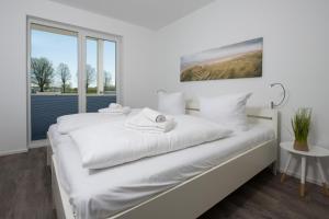 a white bedroom with a white bed and a window at Albatros in Olpenitz