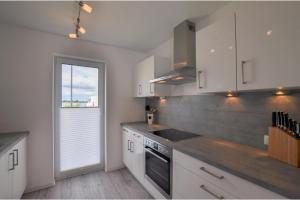 a kitchen with white cabinets and a sink and a window at Nantucket in Olpenitz