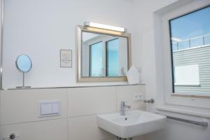 a white bathroom with a sink and a mirror at Achtern Schilf in Olpenitz