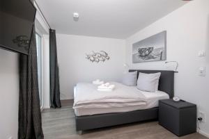 Schlafzimmer mit einem Bett mit weißer Bettwäsche und einem TV in der Unterkunft Silbermöwe in Olpenitz