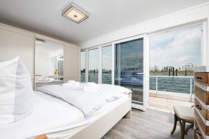 a white bedroom with a view of the water at Schwimmendes Haus Sutsche in Olpenitz