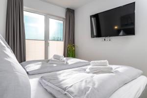 two white beds in a room with a flat screen tv at Landungsbrücke28 in Olpenitz