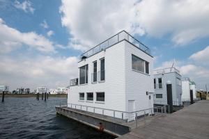 a white house on a dock on the water at Schwimmendes Haus Sutsche in Olpenitz