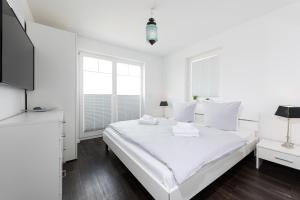 a white bedroom with a large bed and a tv at Danish by Nature in Olpenitz