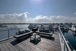 a wooden deck with couches and a table on the water at Schwimmendes Haus Sanibel in Olpenitz