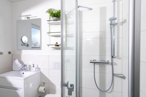 a white bathroom with a shower and a sink at Schwimmendes Haus Sea Lounge in Olpenitz