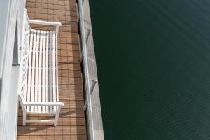 a deck with a white chair and the water at Schwimmendes Haus - Haus im Meer in Olpenitz