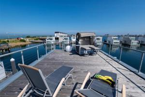 a deck with chairs and chairs on the water at Schwimmendes Haus Sea Lounge in Olpenitz