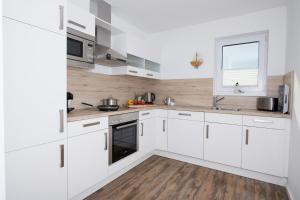 cocina blanca con armarios blancos y ventana en 54 Grad Nord en Olpenitz