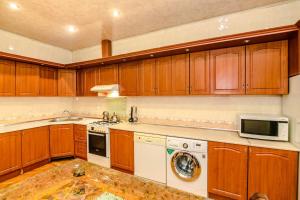 een keuken met houten kasten en een witte vaatwasser bij Mirza Fatali Akhundova 154 Apartment in Baku