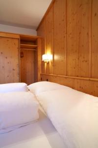 two white beds in a room with wooden walls at Appartements Hotel-Garni Dolce Vita in Samnaun