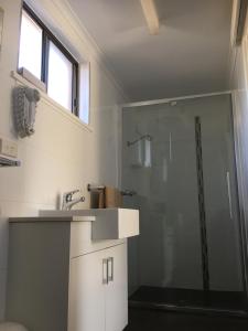 a bathroom with a sink and a glass shower at Deniliquin Motel in Deniliquin