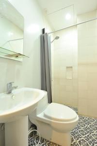 ein weißes Bad mit einem WC und einem Waschbecken in der Unterkunft Down South Hostel in Cebu City