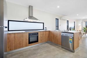 a kitchen with a large flat screen tv on the wall at DAYDREAMING Airlie Beach, Water views & only 200m to boardwalk. in Cannonvale