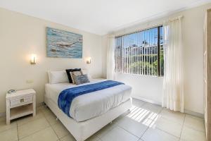 a bedroom with a bed and a window at Smugglers On The Beach in Coffs Harbour