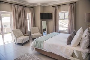 a bedroom with a large bed and two chairs at The Whale on Main B&B in Hermanus +37 photos