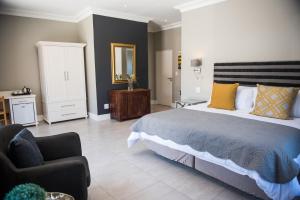 a bedroom with a large bed and a chair at The Whale on Main B&B in Hermanus