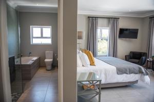 a bedroom with a bed and a bathroom with a tub at The Whale on Main B&B in Hermanus