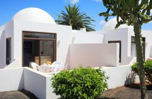 a white house with a palm tree in front of it at H10 Suites Lanzarote Gardens in Costa Teguise