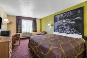 a hotel room with a large bed and a television at Super 8 by Wyndham Fountain in Fountain