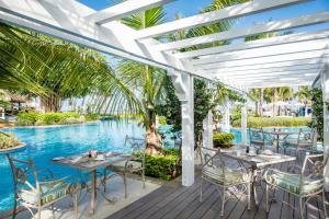 d'une terrasse avec des tables et des chaises à côté de la piscine. dans l'établissement Sugar Beach Mauritius, à Flic-en-Flac