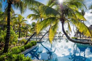- une piscine avec des palmiers dans un complexe dans l'établissement Long Beach Mauritius, à Belle Mare