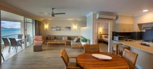 a kitchen and a living room with a table and chairs at Whitsunday Apartments in Hamilton Island