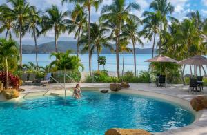 a woman in a pool at a resort with palm trees at Whitsunday Apartments in Hamilton Island