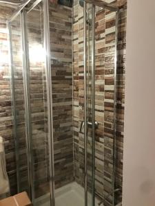 a shower with glass doors and a brick wall at Apartamentos pandiellos I in Madrid