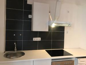 kuchnia ze zlewem i ścianą wyłożoną czarnymi kafelkami w obiekcie Apartamentos pandiellos I w Madrycie