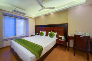 a bedroom with a bed and a desk and a window at Treebo Trend Vedanta in Kolkata