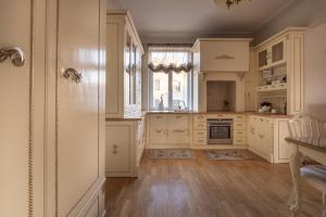 a kitchen with white cabinets and a wooden floor at Broadway apartament in Šiauliai