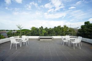 un patio con sedie e tavoli bianchi sul tetto di RedDoorz near Eka Hospital BSD City a Tangerang