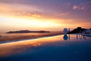 a pool with a sunset in the background at Homeric Poems in Fira