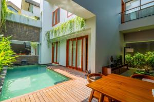 a house with a swimming pool and a wooden deck at Agranusa Signature Villa Nusa Dua in Nusa Dua