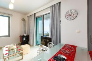 a living room with a glass table and a clock on the wall at Sunset Maisonettes in Plakias