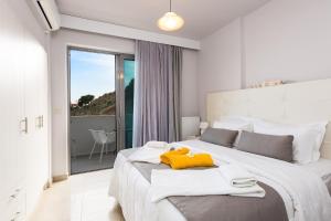 a white bedroom with a large bed with a yellow towel on it at Sunset Maisonettes in Plakias