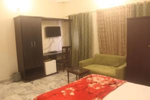 a living room with a bed and a chair and a cabinet at Motel Inn in Karachi