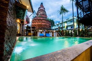 a swimming pool in front of a building with a tower at Chedi Home -SHA Extra Plus in Chiang Mai