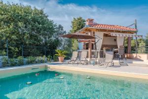 a swimming pool with chairs and an umbrella next to a house at Apartments Jelavić in Sutomišćica