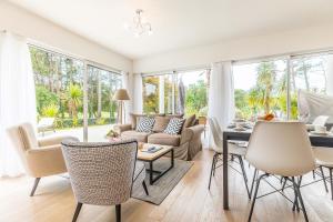 ein Wohnzimmer mit einer Couch und einem Tisch und Stühlen in der Unterkunft Madame Vacances Les Palmiers du Golf Service Premium in Moliets-et-Maa