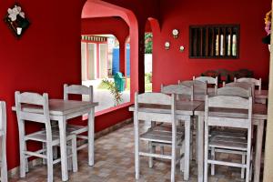 comedor con paredes rojas y mesas y sillas de madera en KR Hostel Ilhabela, en Ilhabela
